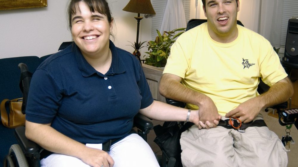 A woman and man in wheelchairs smiling.