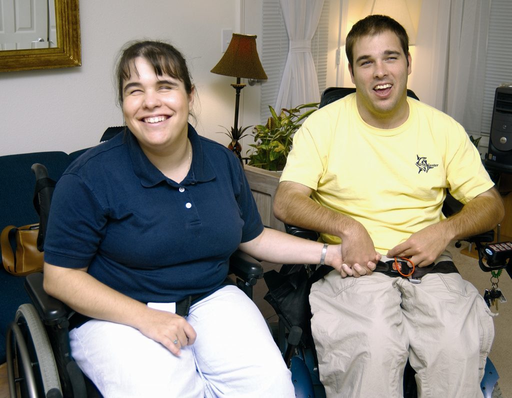 A woman and man in wheelchairs smiling.