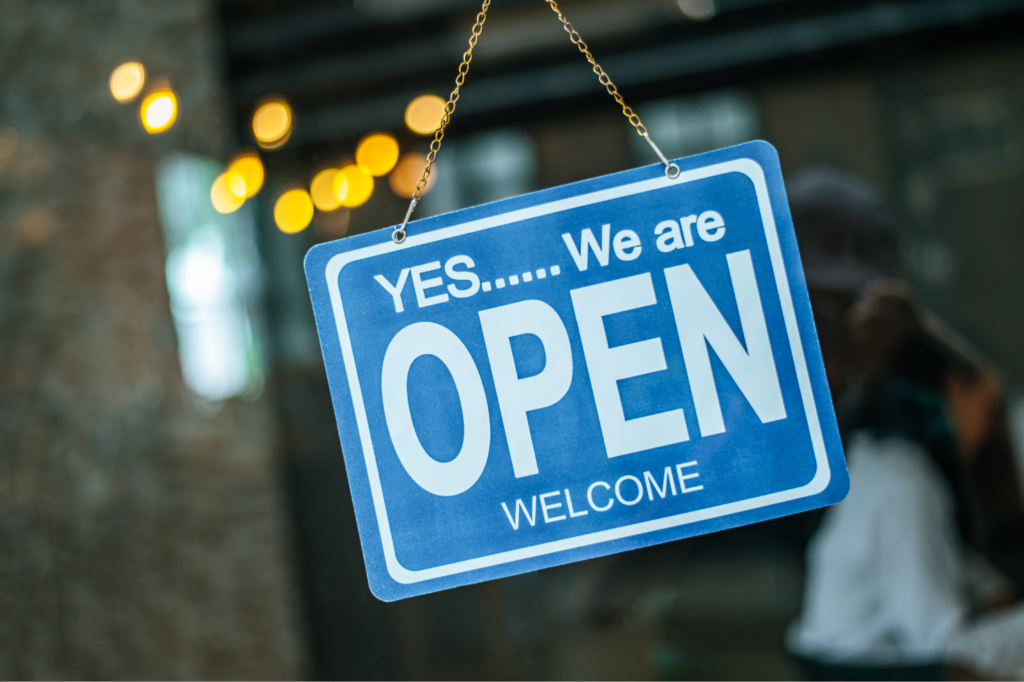 Store front with sign: Yes...we are open. Welcome