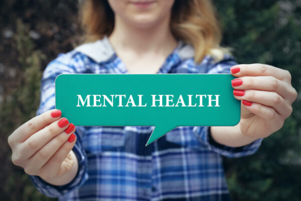 A woman holding a speech bubble sign with the words "mental health"